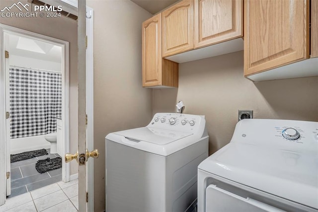 washroom with cabinets, light tile patterned floors, and washing machine and clothes dryer