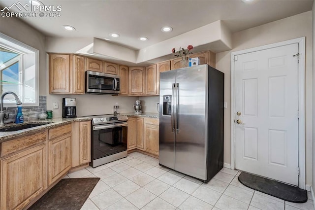 kitchen featuring light brown cabinetry, stainless steel appliances, light stone counters, and sink