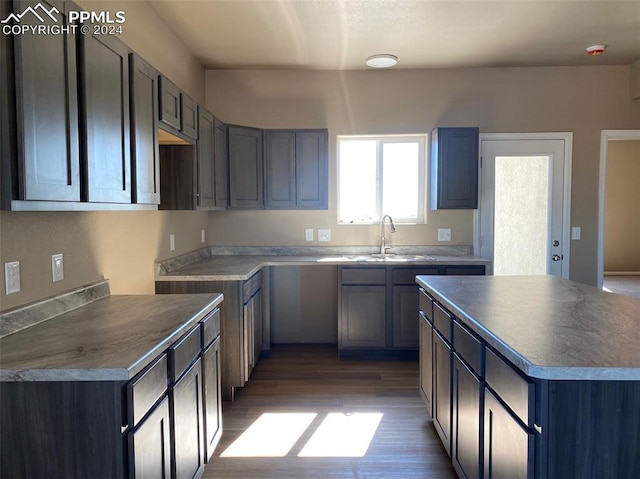 kitchen featuring dark hardwood / wood-style flooring, a center island, gray cabinetry, and sink