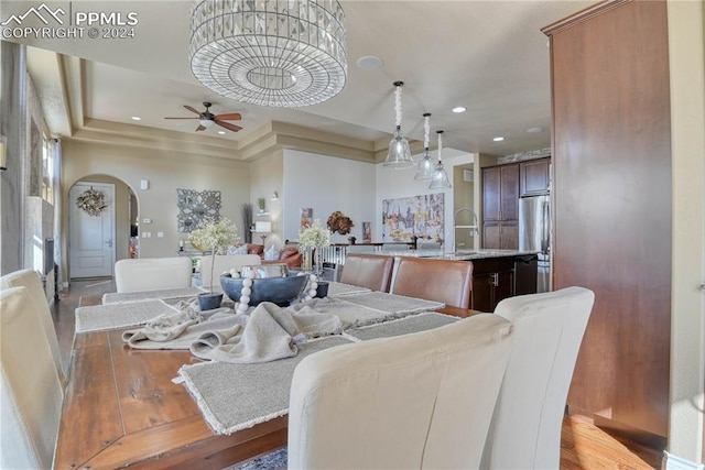 dining space with a tray ceiling, ceiling fan, light hardwood / wood-style flooring, and sink