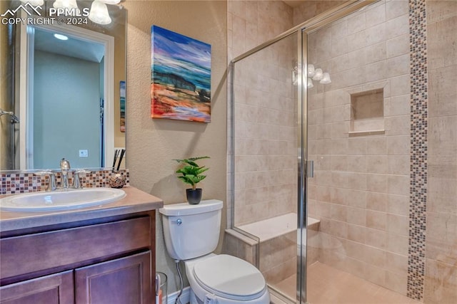 bathroom featuring a shower with door, vanity, and toilet