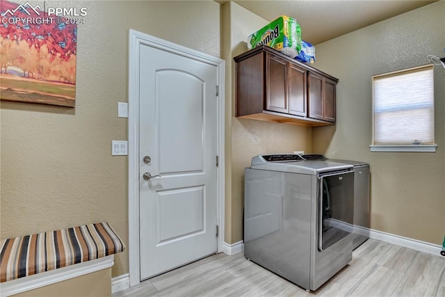 washroom featuring cabinets, washing machine and dryer, and light wood-type flooring