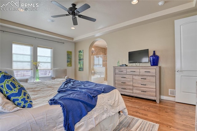 bedroom with connected bathroom, light hardwood / wood-style floors, and ceiling fan