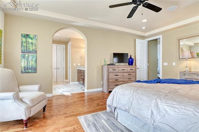 bedroom with light hardwood / wood-style flooring, ensuite bath, and ceiling fan