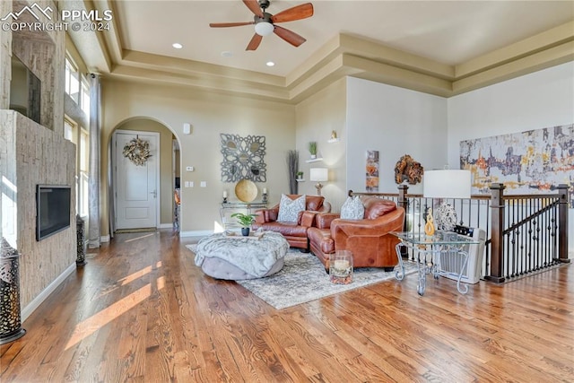 living room with a tray ceiling, wood-type flooring, and a high ceiling