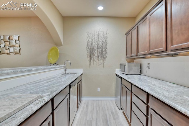 kitchen featuring light stone counters, dishwasher, and sink