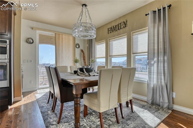 dining area with hardwood / wood-style flooring, plenty of natural light, and a chandelier