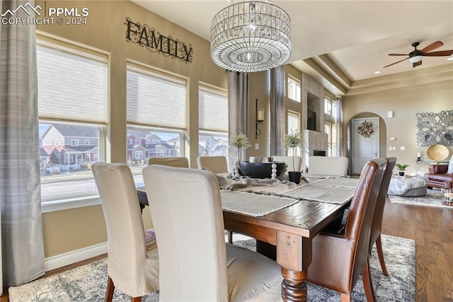 dining area featuring ceiling fan with notable chandelier and wood-type flooring