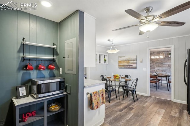 kitchen with crown molding, ceiling fan, hardwood / wood-style floors, electric panel, and black fridge