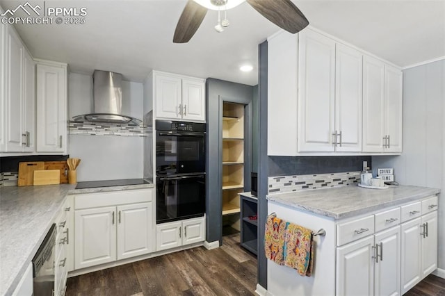 kitchen featuring wall chimney range hood, white cabinets, and black appliances