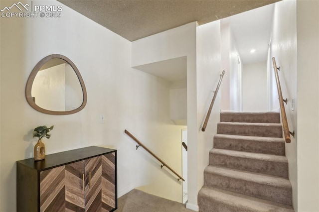 stairway with carpet and a textured ceiling