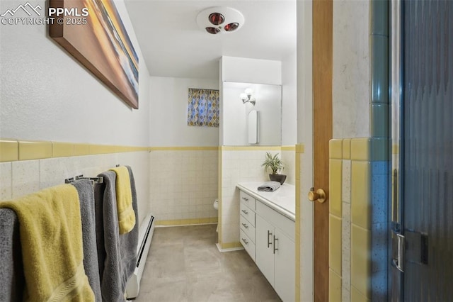 bathroom featuring tile walls, a baseboard heating unit, vanity, an enclosed shower, and toilet