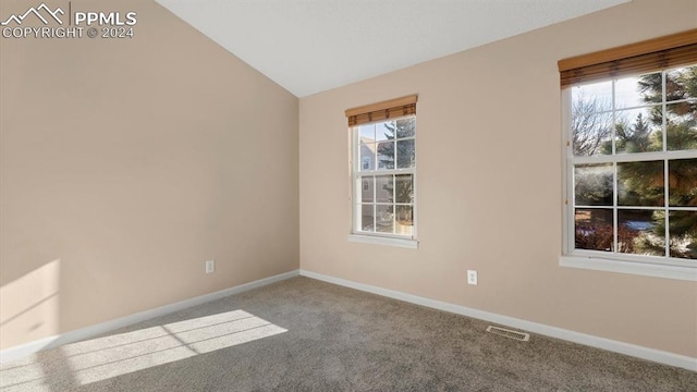 carpeted spare room with vaulted ceiling