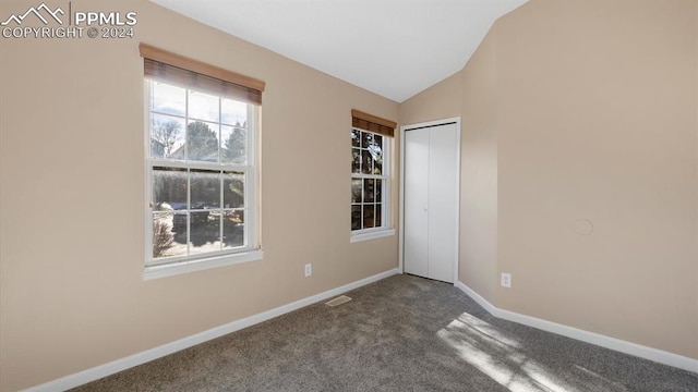 carpeted empty room with vaulted ceiling