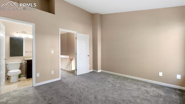 unfurnished bedroom with connected bathroom, a towering ceiling, and carpet floors