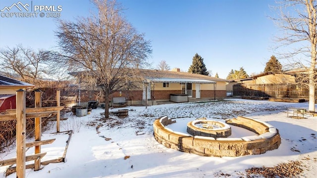 snow covered rear of property with an outdoor fire pit