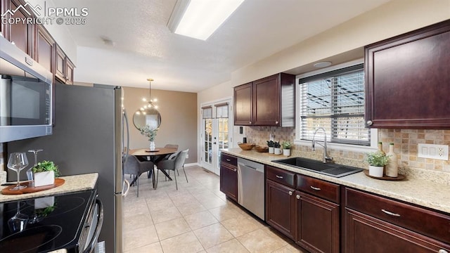 kitchen featuring decorative backsplash, appliances with stainless steel finishes, hanging light fixtures, and sink