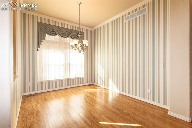 unfurnished room with crown molding, an inviting chandelier, and hardwood / wood-style flooring