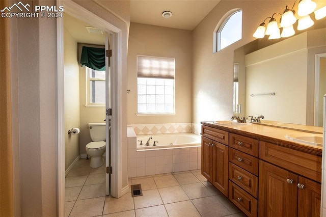 bathroom featuring tile patterned flooring, vanity, a relaxing tiled tub, and toilet