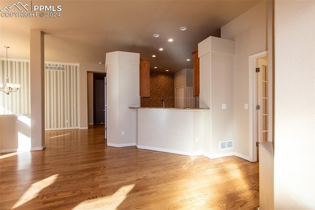 unfurnished living room featuring a chandelier and light wood-type flooring