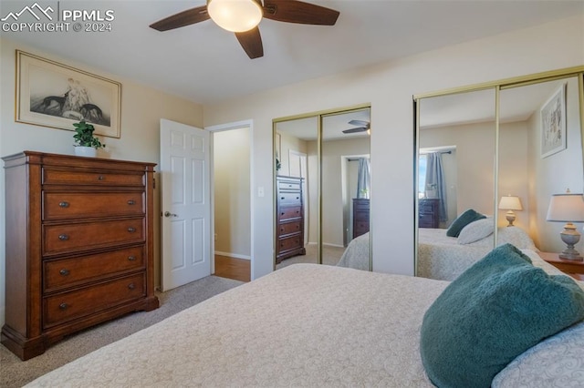 carpeted bedroom featuring ceiling fan and two closets