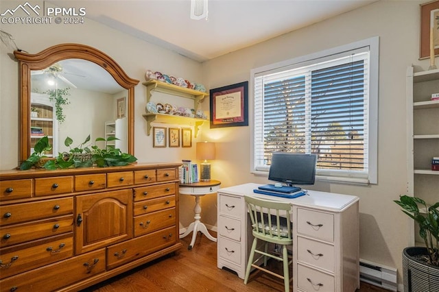 home office with ceiling fan, light wood-type flooring, and a baseboard heating unit