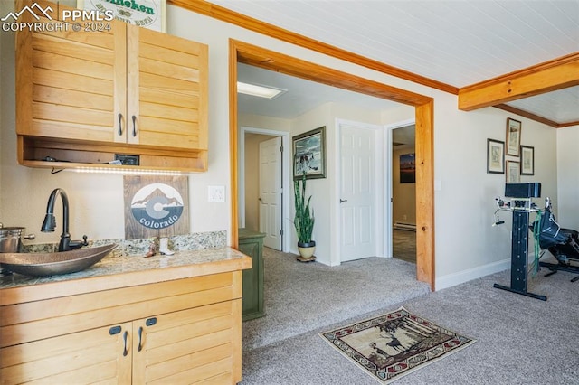 kitchen with light brown cabinets, carpet floors, ornamental molding, and sink