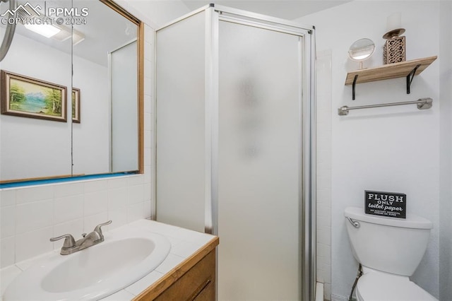 bathroom featuring decorative backsplash, a shower with door, vanity, and toilet