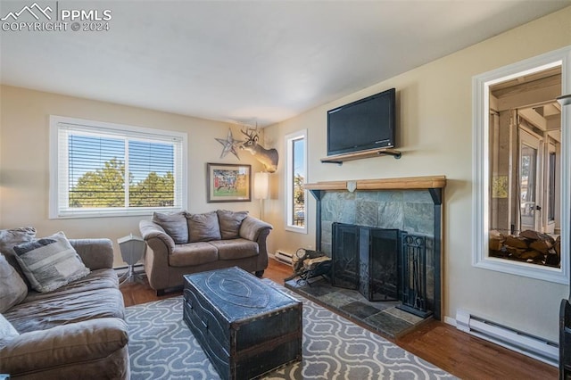 living room featuring dark hardwood / wood-style flooring, a tiled fireplace, and a baseboard heating unit