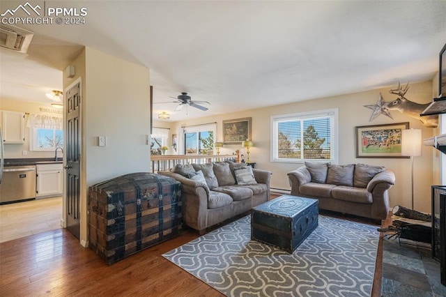 living room with dark hardwood / wood-style floors, a baseboard radiator, ceiling fan, and sink