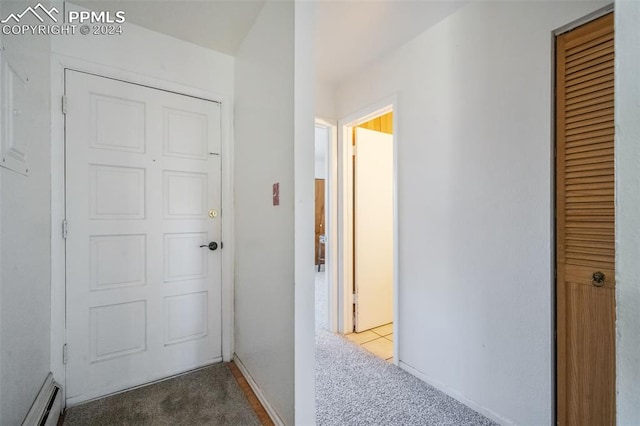 corridor with a baseboard heating unit and carpet floors