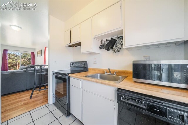 kitchen featuring white cabinets, sink, black appliances, and light tile patterned floors