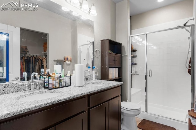 bathroom with vanity, toilet, and a shower with door