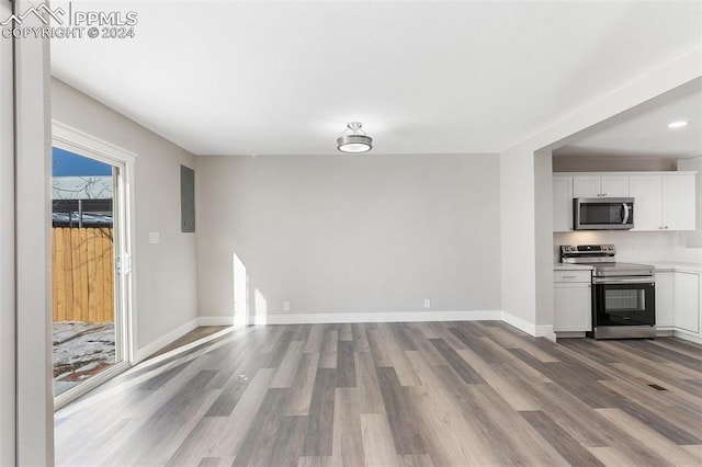 kitchen with appliances with stainless steel finishes, hardwood / wood-style flooring, and white cabinetry