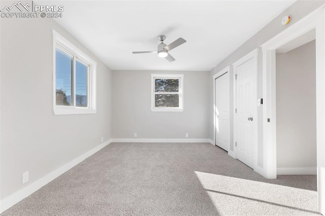 unfurnished bedroom with carpet flooring, multiple windows, and ceiling fan