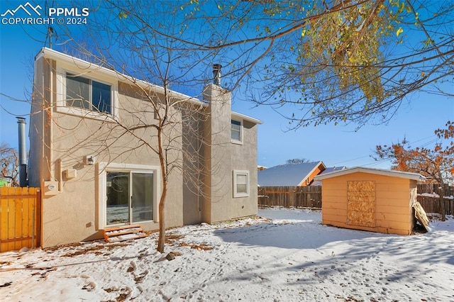 snow covered property with a storage unit