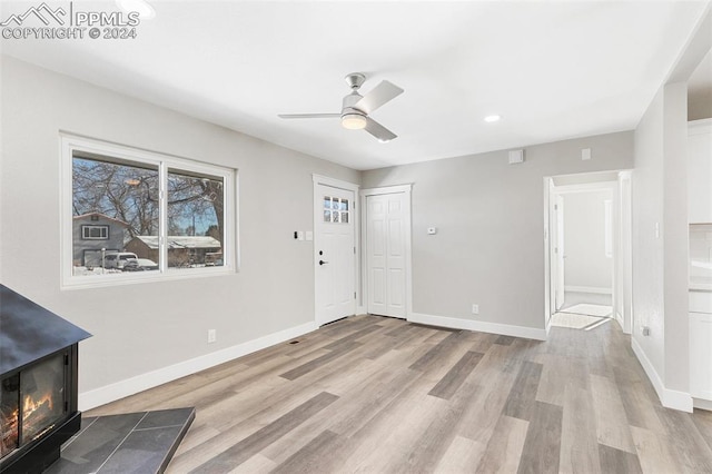 entrance foyer featuring ceiling fan, a wood stove, and light hardwood / wood-style flooring