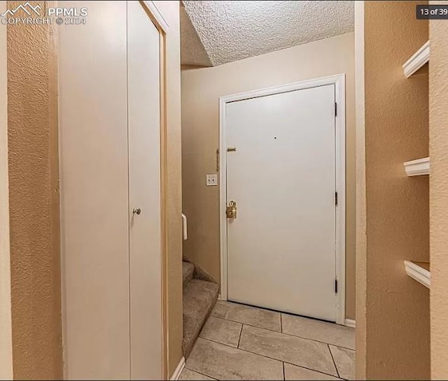 doorway with light tile patterned floors and a textured ceiling