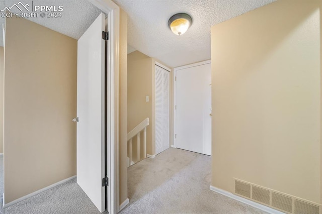 hallway featuring light carpet and a textured ceiling