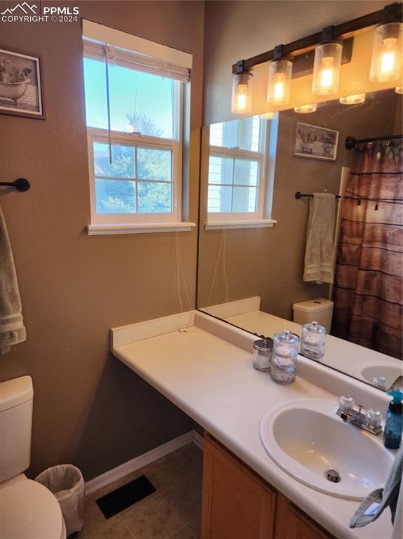 bathroom featuring tile patterned floors, curtained shower, vanity, and toilet