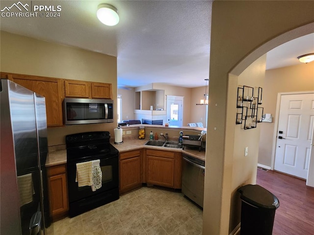 kitchen with decorative light fixtures, stainless steel appliances, light hardwood / wood-style floors, and sink