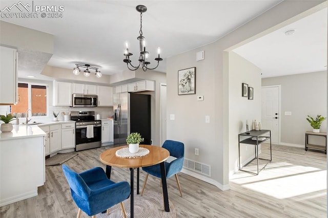 dining space featuring light wood-type flooring, sink, and an inviting chandelier