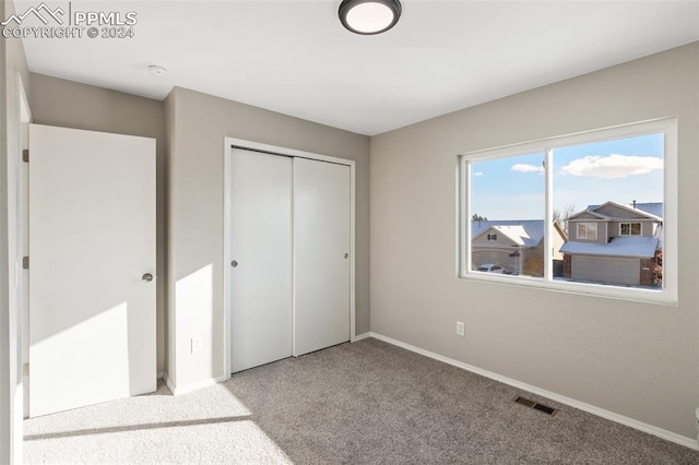 unfurnished bedroom featuring light colored carpet and a closet