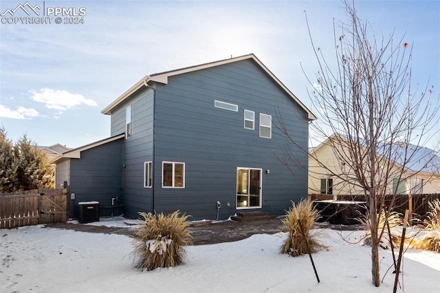 snow covered rear of property featuring central air condition unit