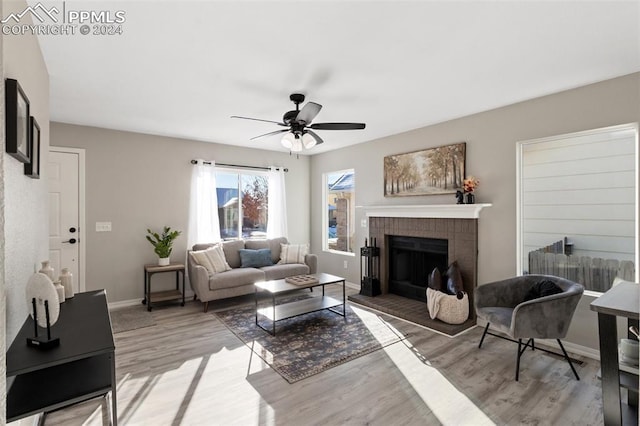 living room with a fireplace, light hardwood / wood-style flooring, and ceiling fan