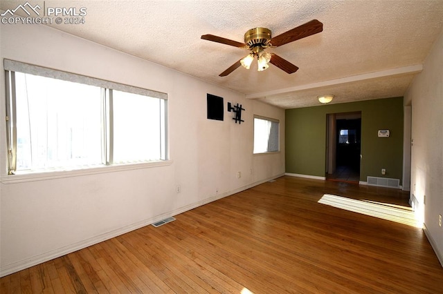 empty room with ceiling fan, wood-type flooring, and a textured ceiling