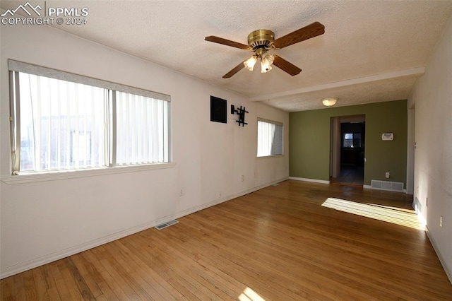 spare room featuring wood-type flooring, a textured ceiling, plenty of natural light, and ceiling fan