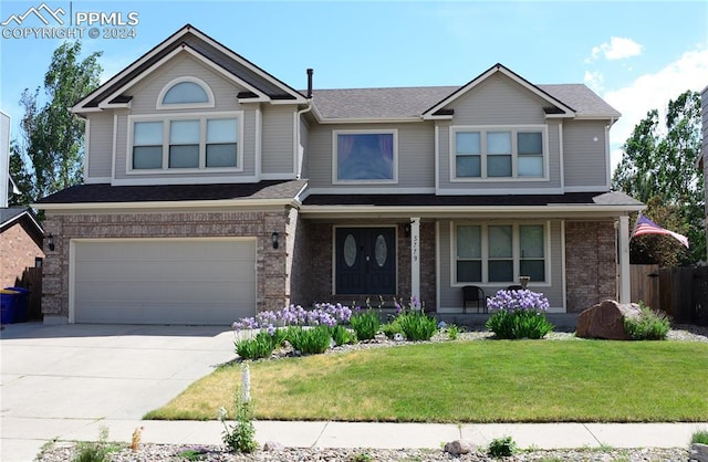 view of front of home featuring a porch, a front yard, and a garage