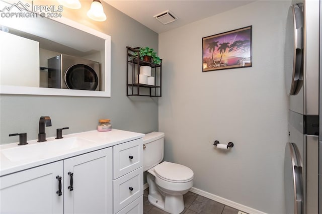 bathroom featuring tile patterned flooring, vanity, toilet, and stacked washer / dryer