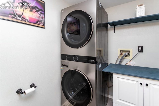 laundry room featuring cabinets and stacked washer and dryer